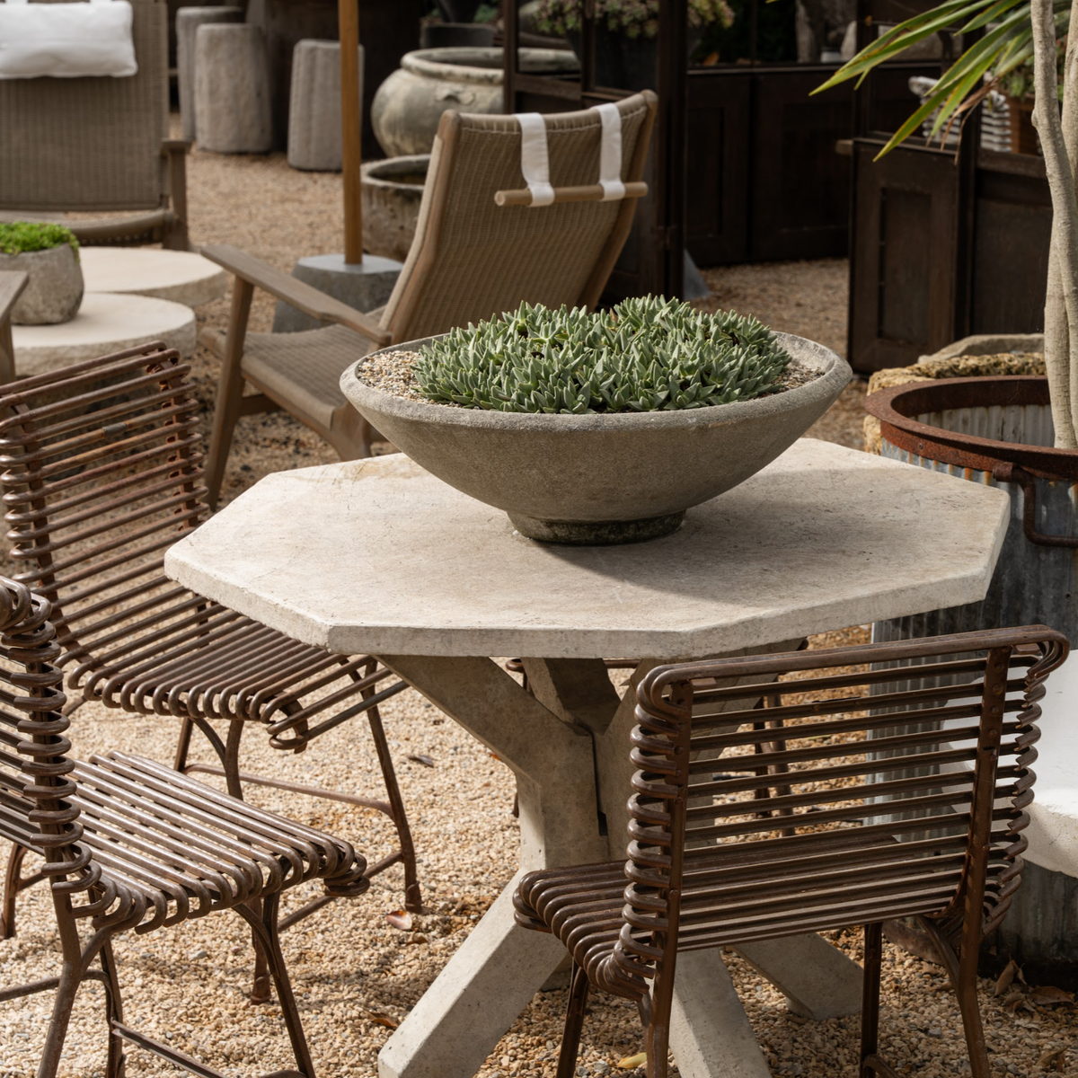 The Well by BDAntiques rust-colored metal outdoor chair with a curved iron rod design on a patio setting.