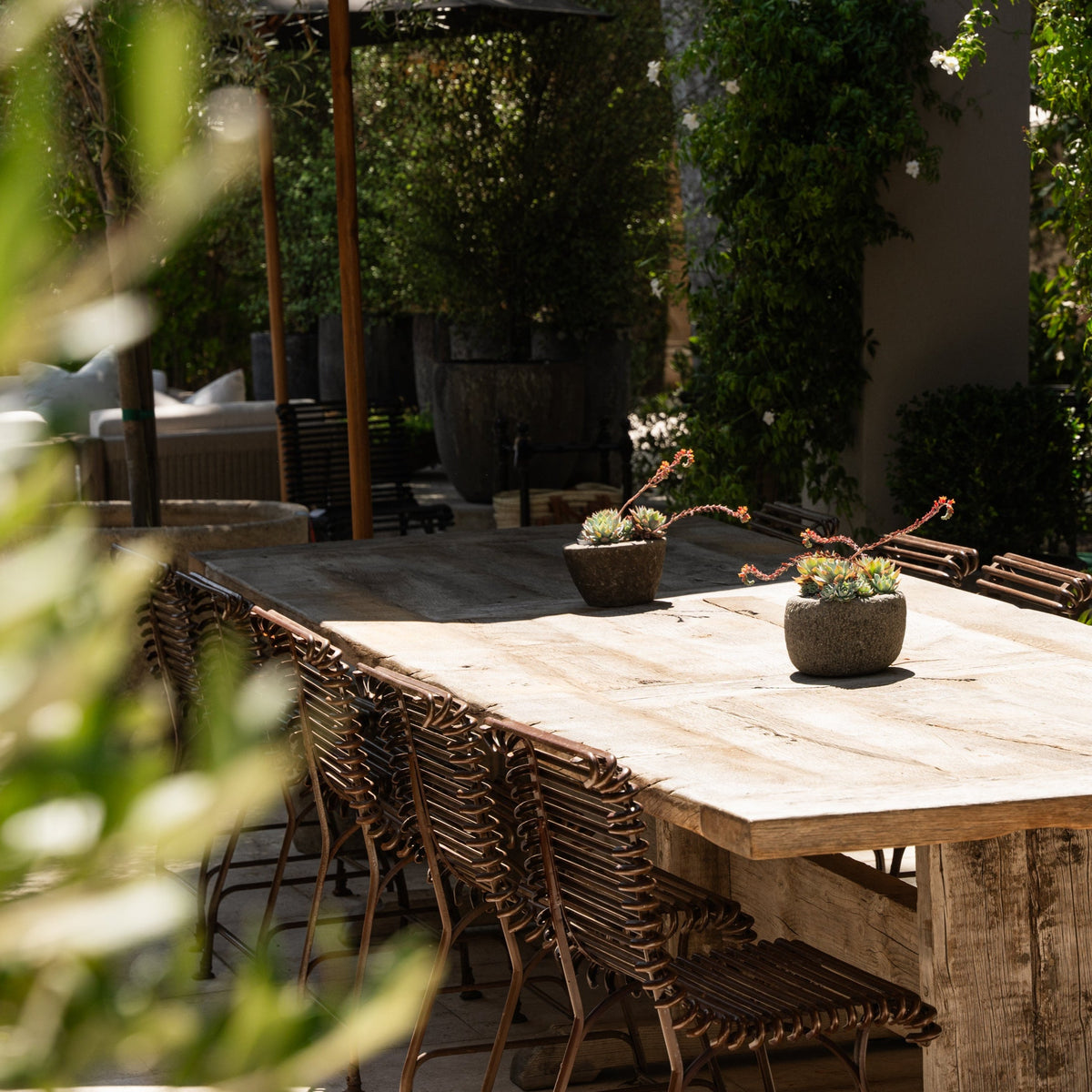 The Well by BDAntiques rust-colored metal outdoor chairs with curved iron rod design arranged around a wooden table.