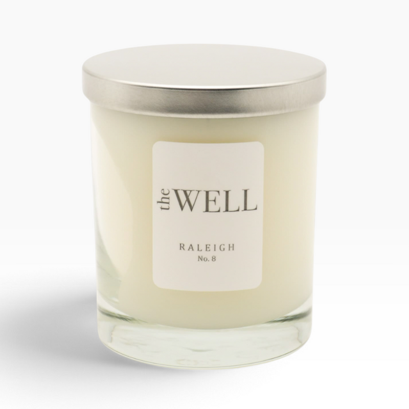 The Well by BDAntiques No. 8 soy wax candle in a clear blown glass vessel with a silver lid on a white background.