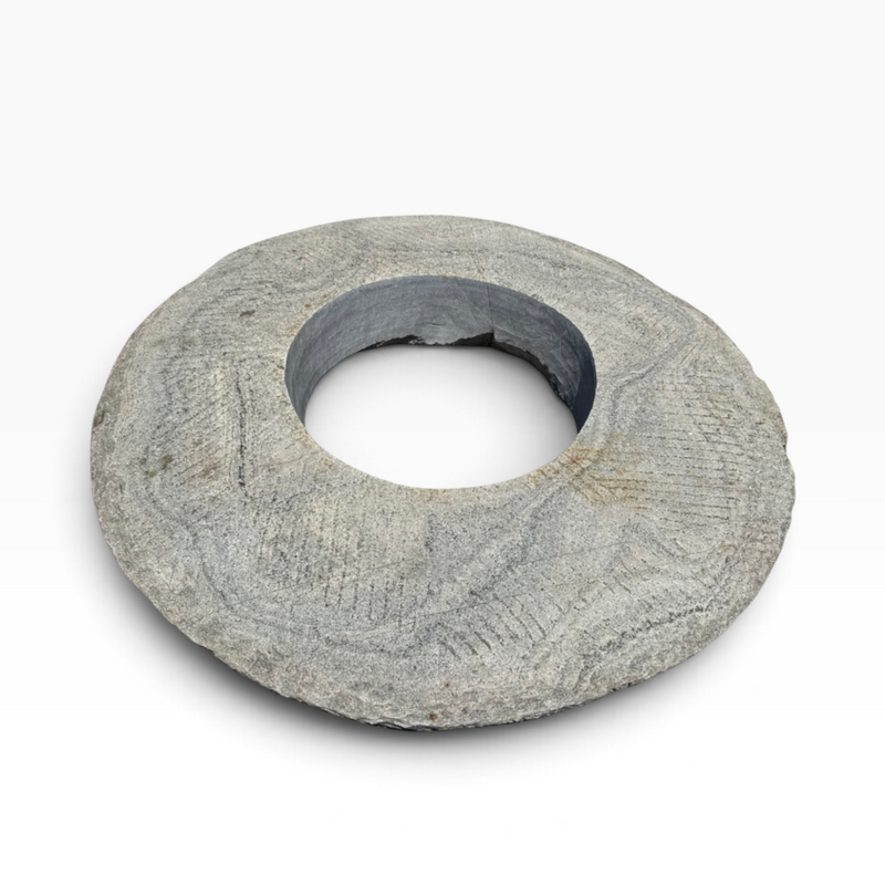 The Well by BDAntiques vintage millstone fire pit with a weathered grey stone texture and a central circular opening.