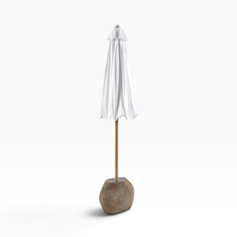 The Well by BDAntiques white patio umbrella with a wooden pole and natural stone base, closed and upright.